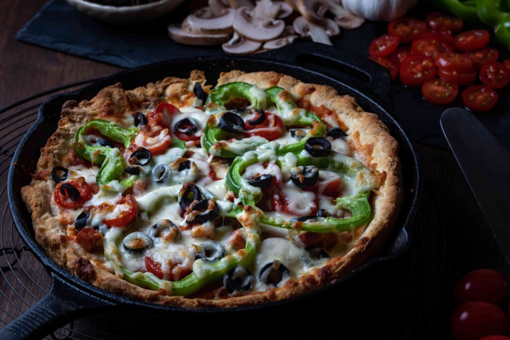 Large deep dish deluxe pan pizza against a dark background.